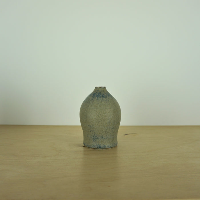 a small blue grey coloured handmade ceramic vase on a table. 