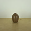 a small brown / tamba coloured handmade ceramic vase on a table. 