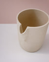 Beige ceramic cup on a white surface with a pink background. Handmade Stoneware 500ml Carafe by BRUTES Ceramics | Shop Fodder