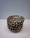 Stack of black and white checkered bowls on a white surface with a grey background