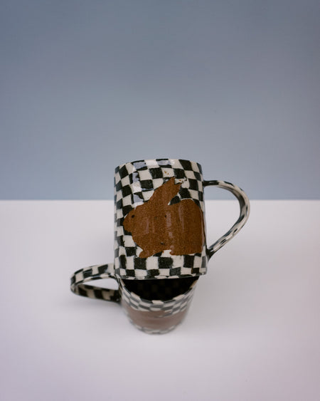 Ceramic mug with checkered pattern and brown abstract design on a white surface. Bunny Mugs by Ceramicist Fern Taylor | Shop Fodder