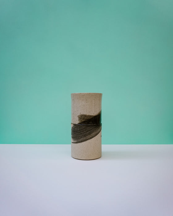 Cylindrical ceramic vase with black abstract design on a light green background. Janne Meijer Ceramics | Shop Fodder