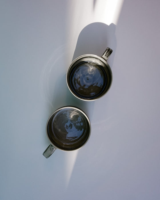 Two metallic cups with reflective surfaces on a white background.  Janne Meijer Ceramics | Shop Fodder