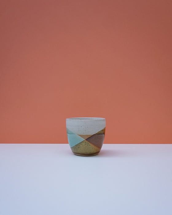 Ceramic cup with geometric design on a peach background. Liz Vidal Ceramics | Shop Fodder