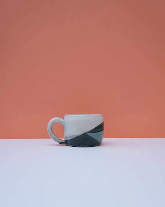 Ceramic mug with a black and white design on a peach and white background. Liz Vidal Ceramics | Shop Fodder