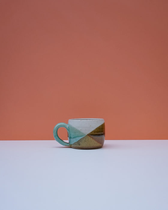 Ceramic mug with geometric design on a peach and white background. Liz Vidal Ceramics | Shop Fodder