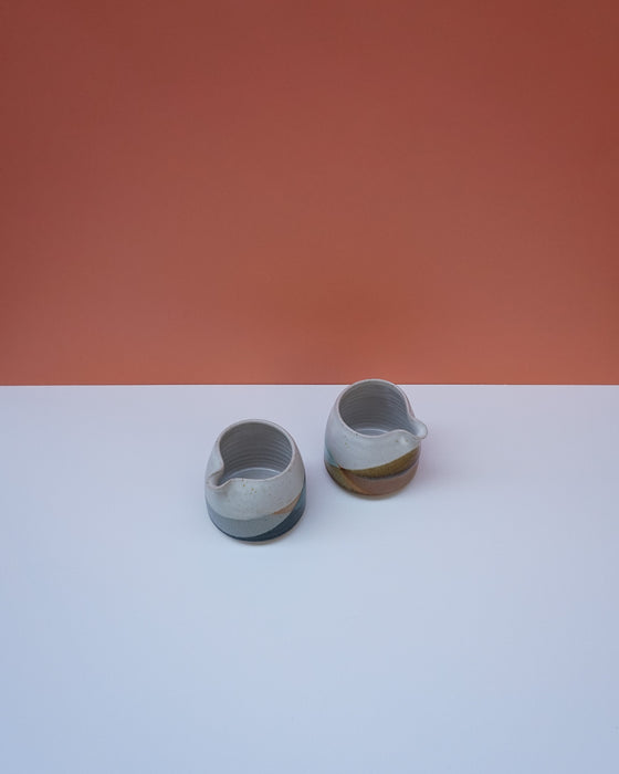 Two ceramic items on a white surface with a red background. Liz Vidal Ceramics | Shop Fodder
