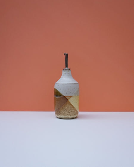 Ceramic bottle with geometric design on a peach background. Liz Vidal Ceramics | Shop Fodder