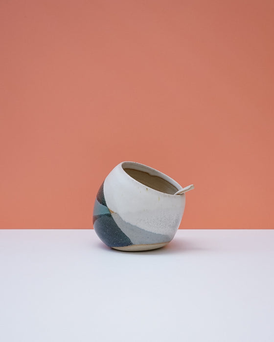 Ceramic pot with geometric design on a white surface and peach background. Liz Vidal Ceramics | Shop Fodder