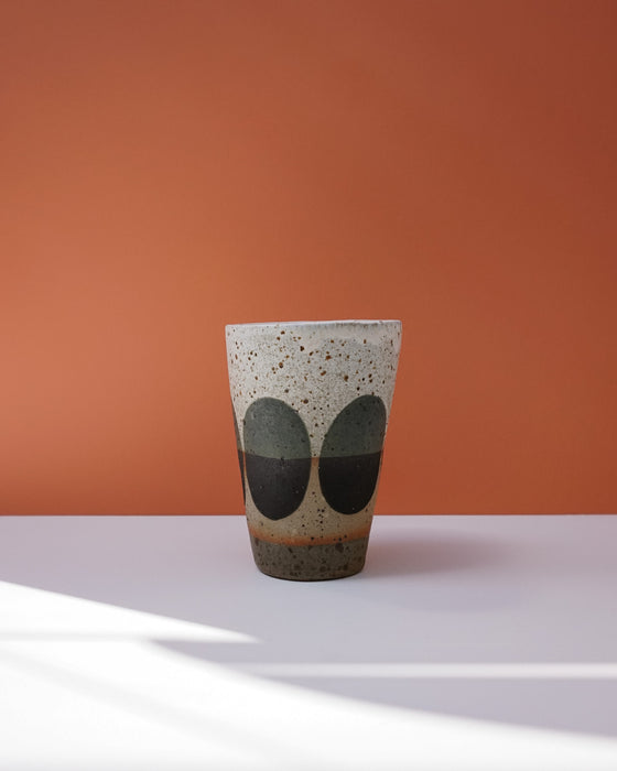 Ceramic cup with speckled pattern on a peach background. Sophie Alda | Handmade Ceramics | Shop Fodder