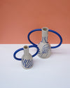 Two ceramic vases with blue handles on a white surface against an orange background. Sophie Alda | Handmade Ceramics | Shop Fodder
