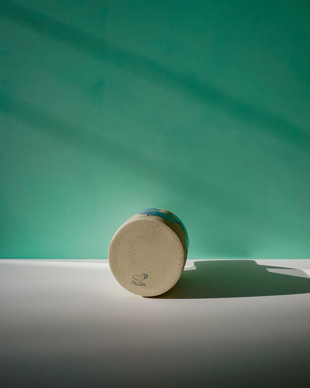 Round wooden object with a brand logo on a green background. Sophie Alda | Handmade Ceramics | Shop Fodder