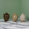 three handmade ceramic budvases with fingerprints in the glaze on a marble table with a green background. 