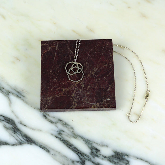 Necklace with a floral pendant on a maroon card against a marble background | Square_Dissarray_Pendant_Scarlett_Cohen_French_Shop_Fodder_