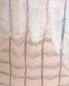 handmade jug with a crosshatch pattern and yellow handle on a marble table with a green background. 