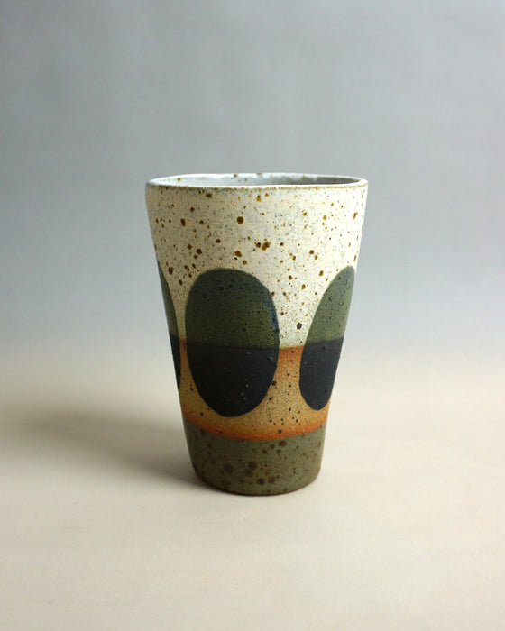 Speckled ceramic cup with green and orange design on a gradient background. Sophie Alda | Shop Fodder